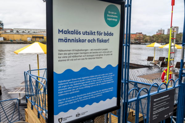 Informationsskylt vid kajbalkong på Reimersholme i Stockholm med text om projektet och dess inriktning